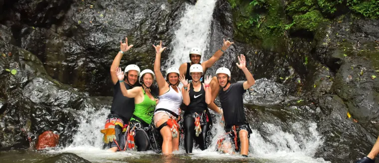 A group in helmets under a waterfall